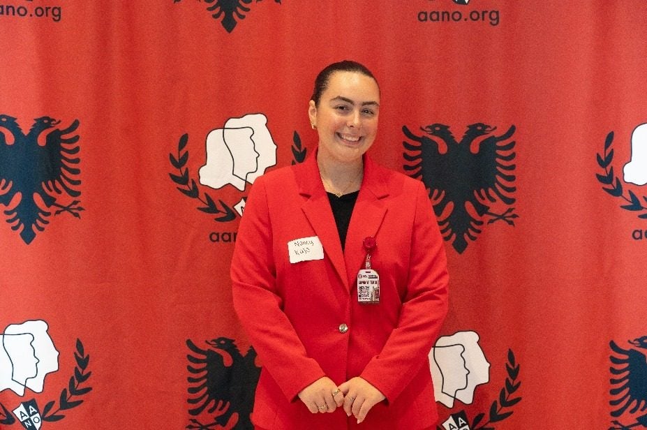 Një anëtare e komitetit organizues përpara sfondit të AANO-s.