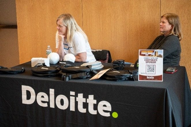 Përfaqësuese të Deloitte te tavolina e tyre me një kartë QR për sponsorët korporativë.