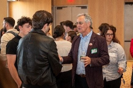 Një profesionist në bisedë me një grup studentësh gjatë pushimit për networking.
