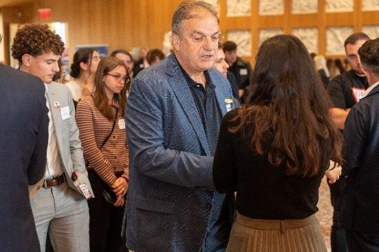 Një pjesëmarrës duke përshëndetur studentët teksa kalon mes turmës.