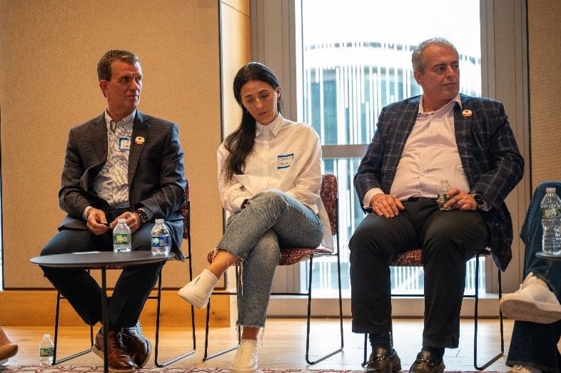 Tre panelistë të ulur mbi skenë gjatë një seance.