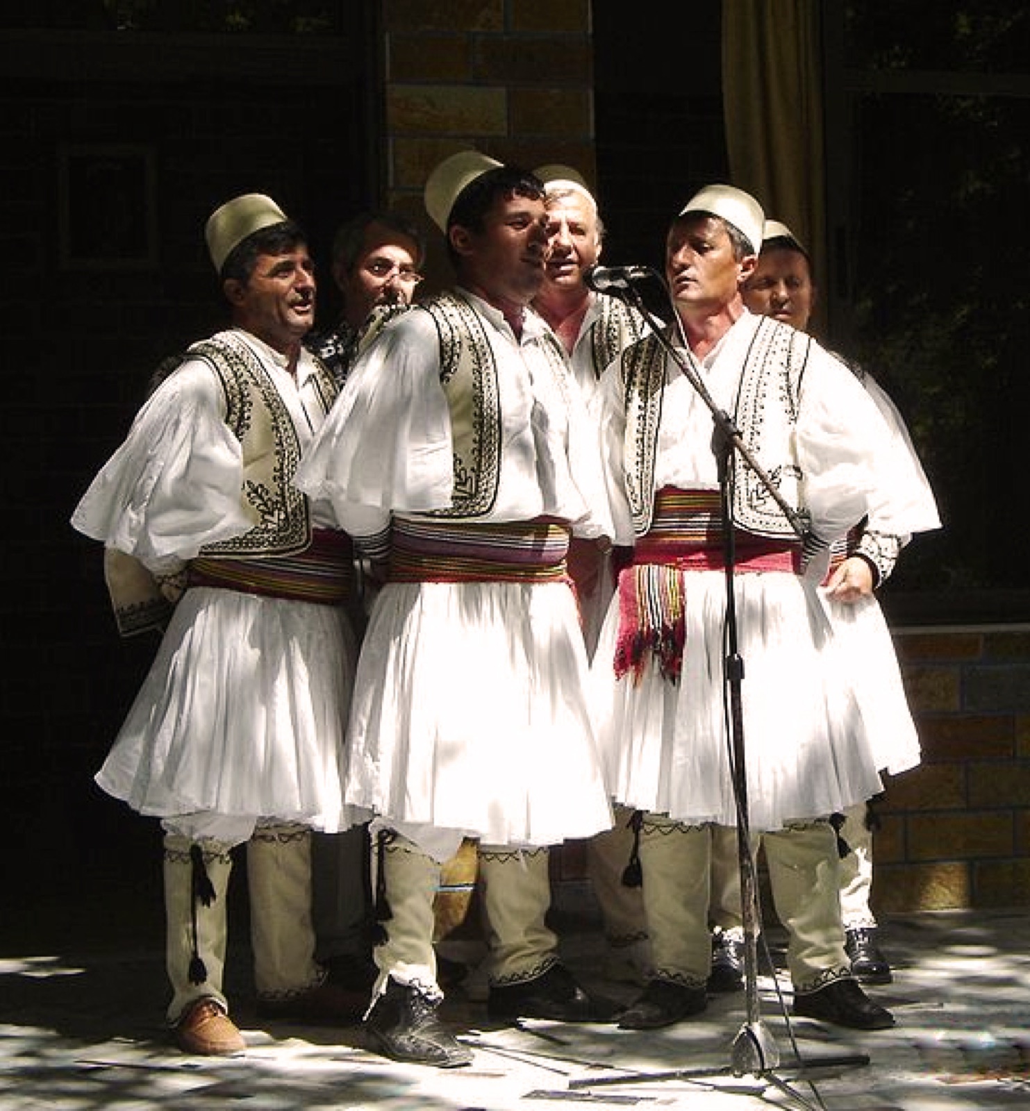 A southern Albanian folk group in fustanella performing on stage — the standard iso-polyphony lineup.