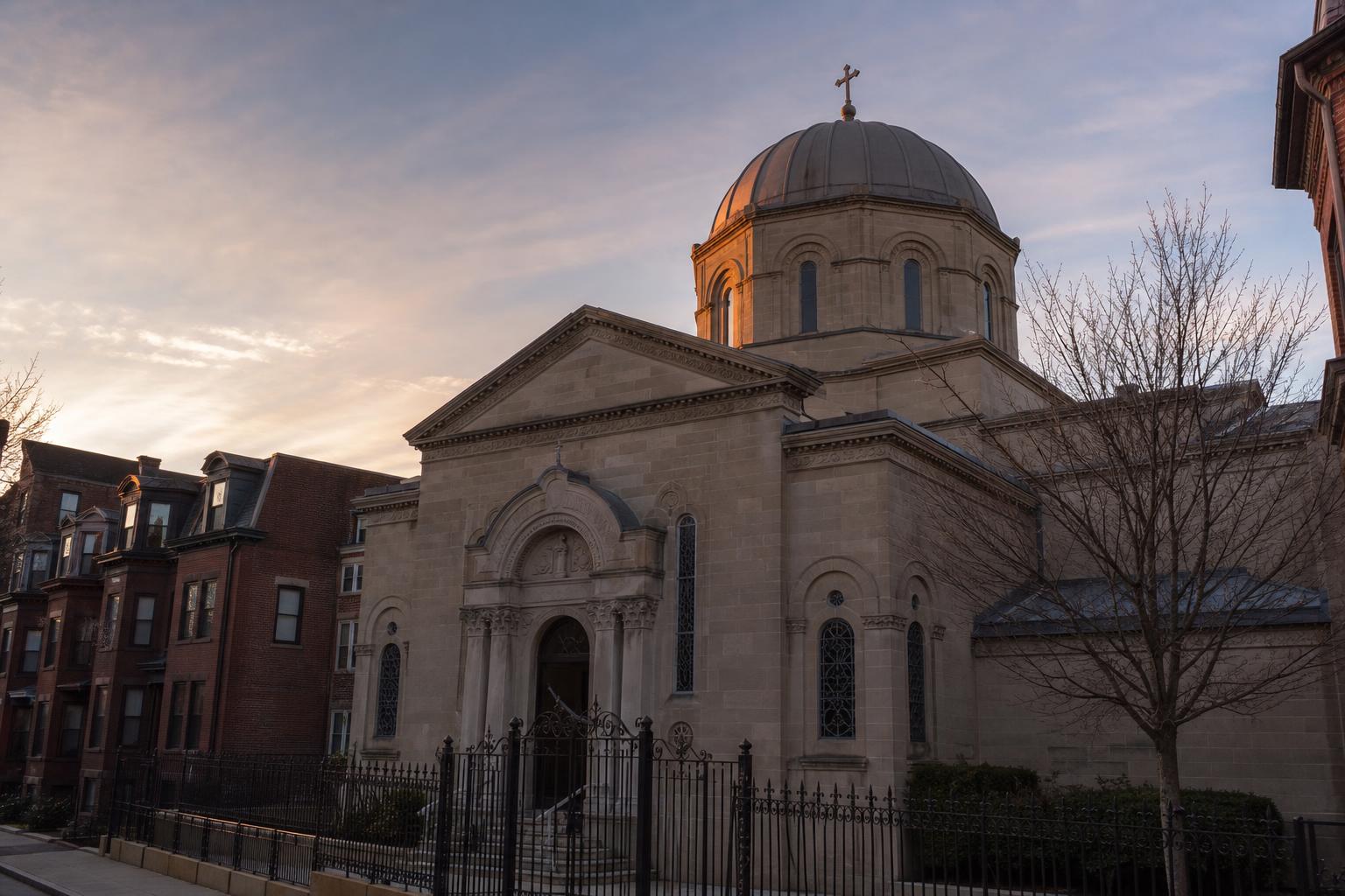 Exterior of an early-20th-century Albanian Orthodox parish church in Boston at dusk, stone facade and a small dome catching the last light.