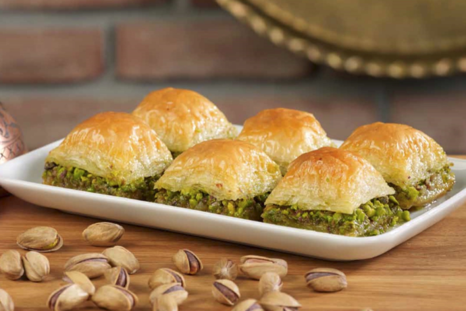 A close-up of fresh baklava, golden filo layers visible, cut in diamond shapes — the same form that appears across Albanian, Turkish, Greek, and Levantine kitchens.